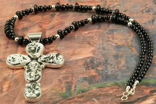Stunning Cross Pendant featuring Genuine White Buffalo Turquoise set in Sterling Silver. The Cross Pendant is on a Genuine Black Onyx Necklace with Sterling Silver Beads and Clasp. This Beautiful Stone is formed from the minerals Calcite and Iron. It is mined near Tonopah Nevada. Created by Navajo Artist Evelyn Yazzie. Signed by the artist.